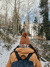 Rear view of woman in winter clothes hiking in nature. forest, snow, exploring, backpack.
