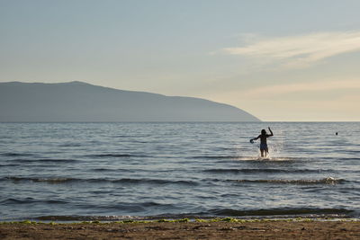 Silhouette man standing on beach against sky