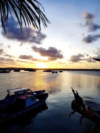 Boats moored in lake against sky during sunset