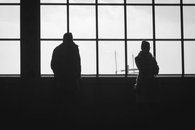 Rear view of silhouette man standing at airport