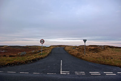 Road sign on highway against sky