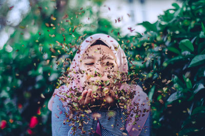 Portrait of woman blowing dry leaves outdoors