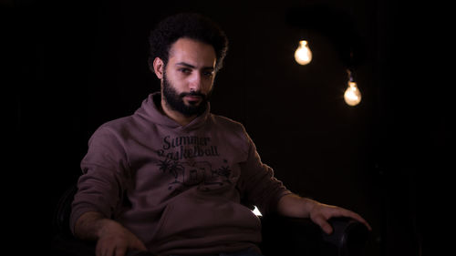Portrait of man sitting in darkroom