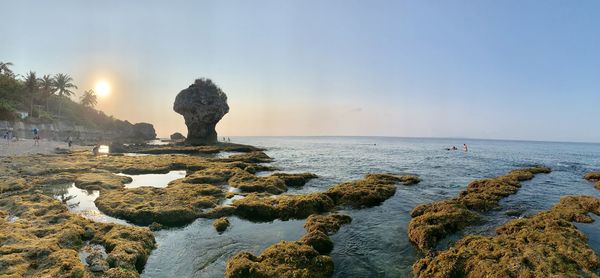 Rock formation on beach against sky