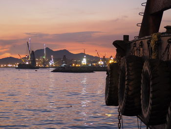 Boats moored at harbor against sky during sunset