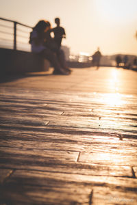 People on pier against sky during sunset