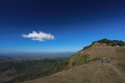 People riding motorcycle on landscape against sky