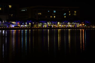 Illuminated buildings by river at night