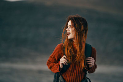 Young woman looking away while standing outdoors