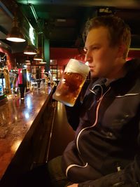 Midsection of man drinking glass on table at restaurant
