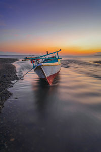 Boat in sea against sky during sunset