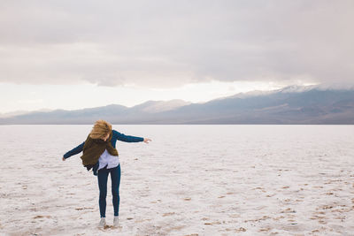 Woman standing by sea against sky