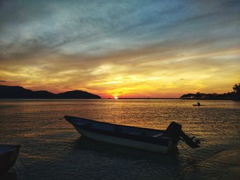 Boat moored on sea against sky during sunset