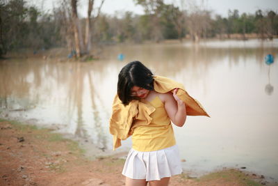 Rear view of woman standing by lake