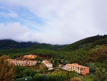 Houses by trees and buildings against sky