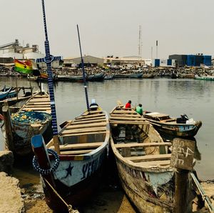 Boats moored at harbor against sky