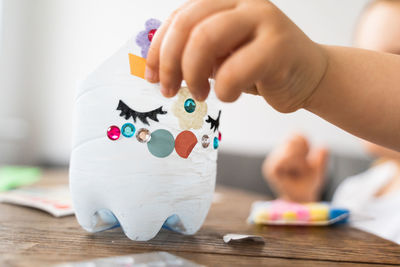 Girl decorating plastic bottle at home