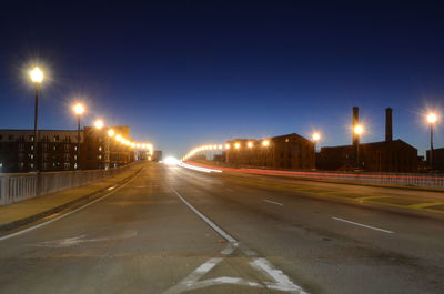 Illuminated light trails on road against sky at night