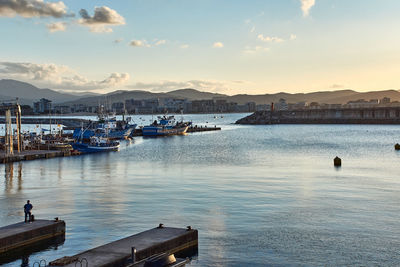 Boats moored at harbor against sky