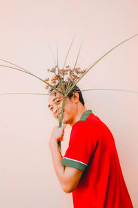 Man holding red flower against white background