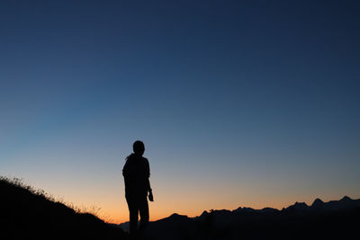 Rear view of woman standing against clear sky in the mountains 