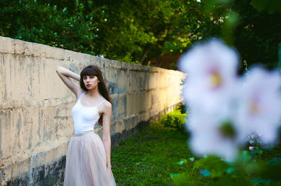 Close-up of flowers against young woman standing at park