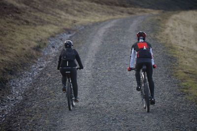 Rear view of men riding bicycle on street