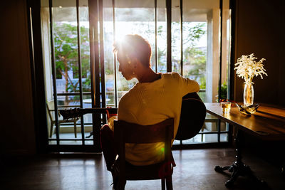 Man playing guitar while sitting on chair at home