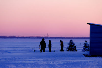 Ice fishing at sunset on the frozen lake.