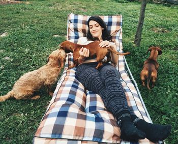 Full length of woman with dogs relaxing on lounger
