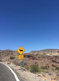 Road sign against clear blue sky