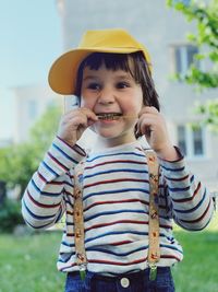 Portrait of a funny boy standing outside and biting some green plant