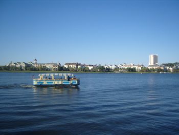 Boats in calm sea against clear sky