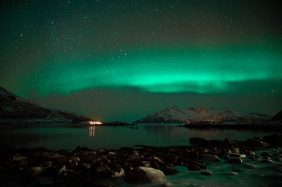 Scenic view of lake and mountains against sky at night