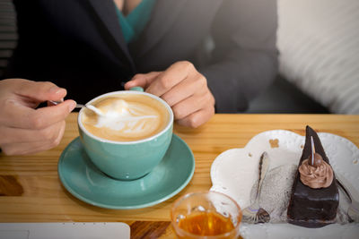 Midsection of man holding coffee cup on table