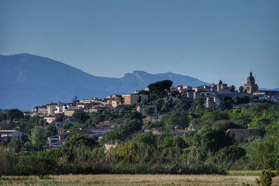 Townscape by mountains against clear blue sky