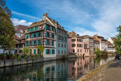 Buildings by canal against sky in city