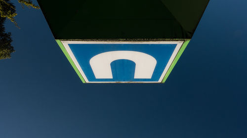 Low angle view of road sign against clear blue sky