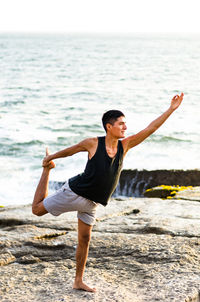 Full length of man doing yoga at beach