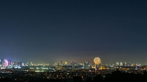 Illuminated cityscape against sky at night