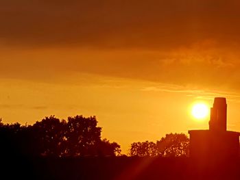 Silhouette trees against orange sky