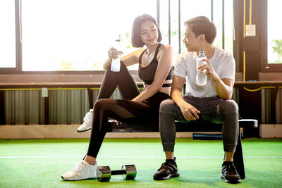 Full length of young couple sitting on window