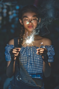 Young woman holding sparklers at night