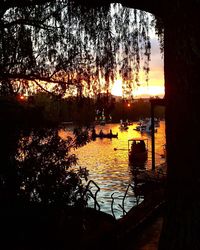 Silhouette trees by lake against sky during sunset