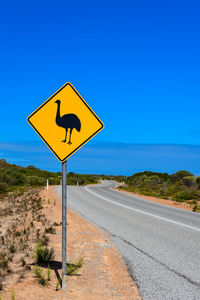 Road sign against clear blue sky