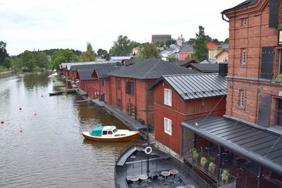 Houses by river and buildings against sky