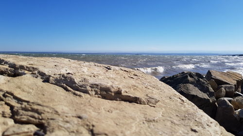 Scenic view of rocky beach against clear blue sky