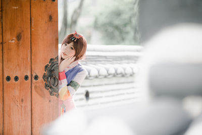 Full length of woman standing against fence