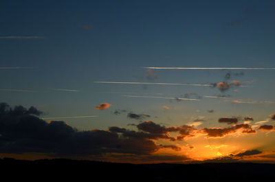 Silhouette airplane flying against sky during sunset