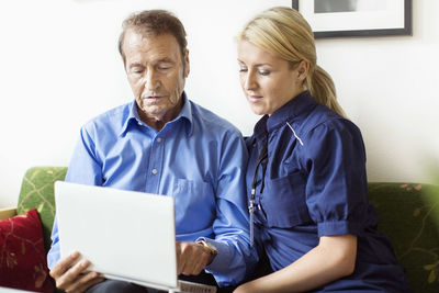 Female caretaker and senior man using laptop at nursing home